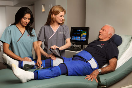 Two clinicians prepare a patient for an EECP Flow Therapy treatment.