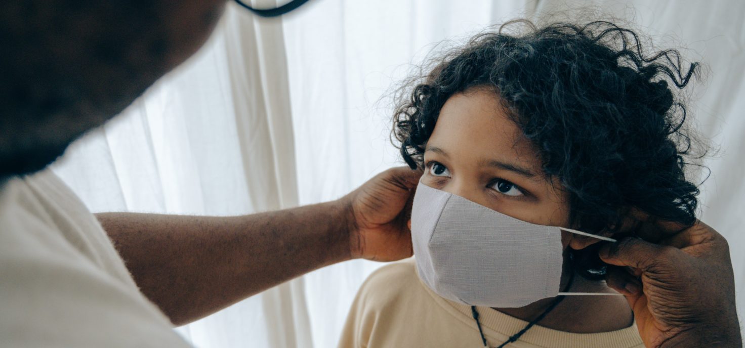 Long COVID kid wearing a mask in front of a doctor